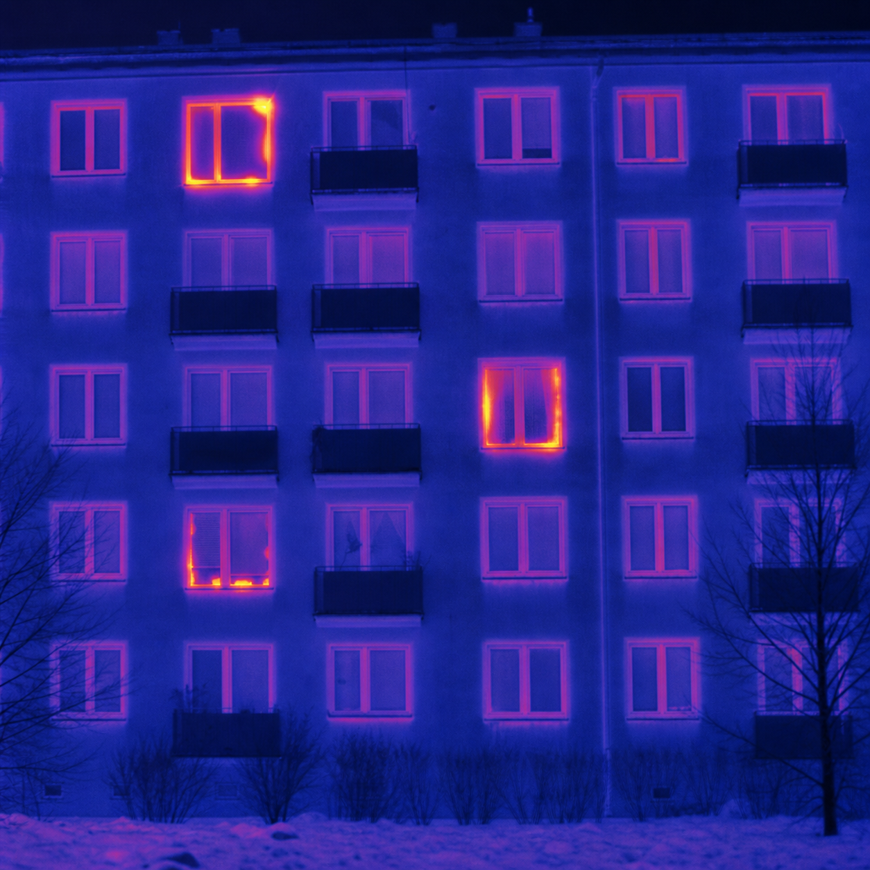 Termowizja bloku pokazująca nierówne straty ciepła przez trzy nieszczelne okna